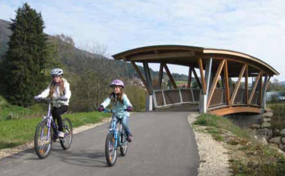 Deux jeunes filles à vélo viennent de franchir le pont cyclable.